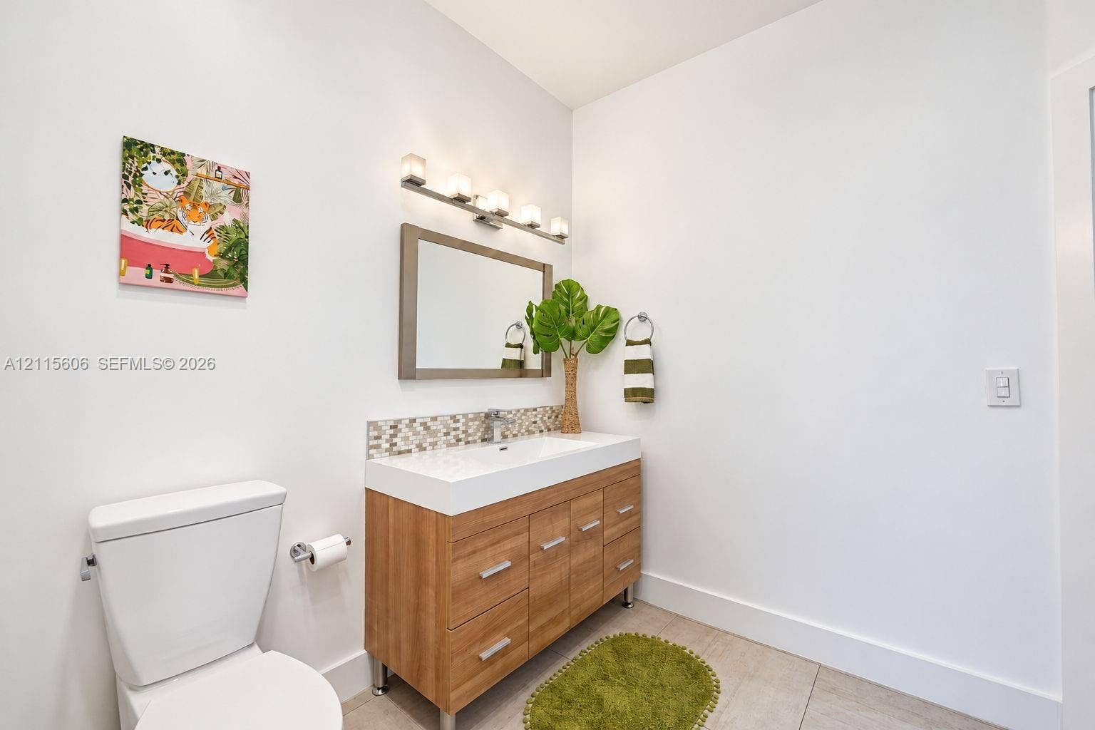 2652 Palmer Place, #2652, Weston, Weston, FL 33332 Wood-finish vanity with a rectangular sink, multi-tone glass tile backsplash, framed wall mirror, and chrome multi-bulb light fixture
