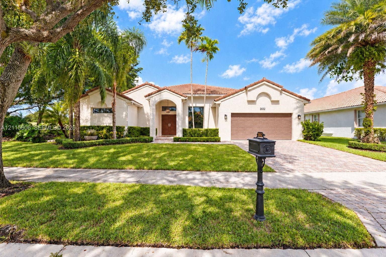 2652 Palmer Place, #2652, Weston, Weston, FL 33332 Stucco exterior featuring a clay tile roof, arched entryway, paved driveway, and mature landscaping