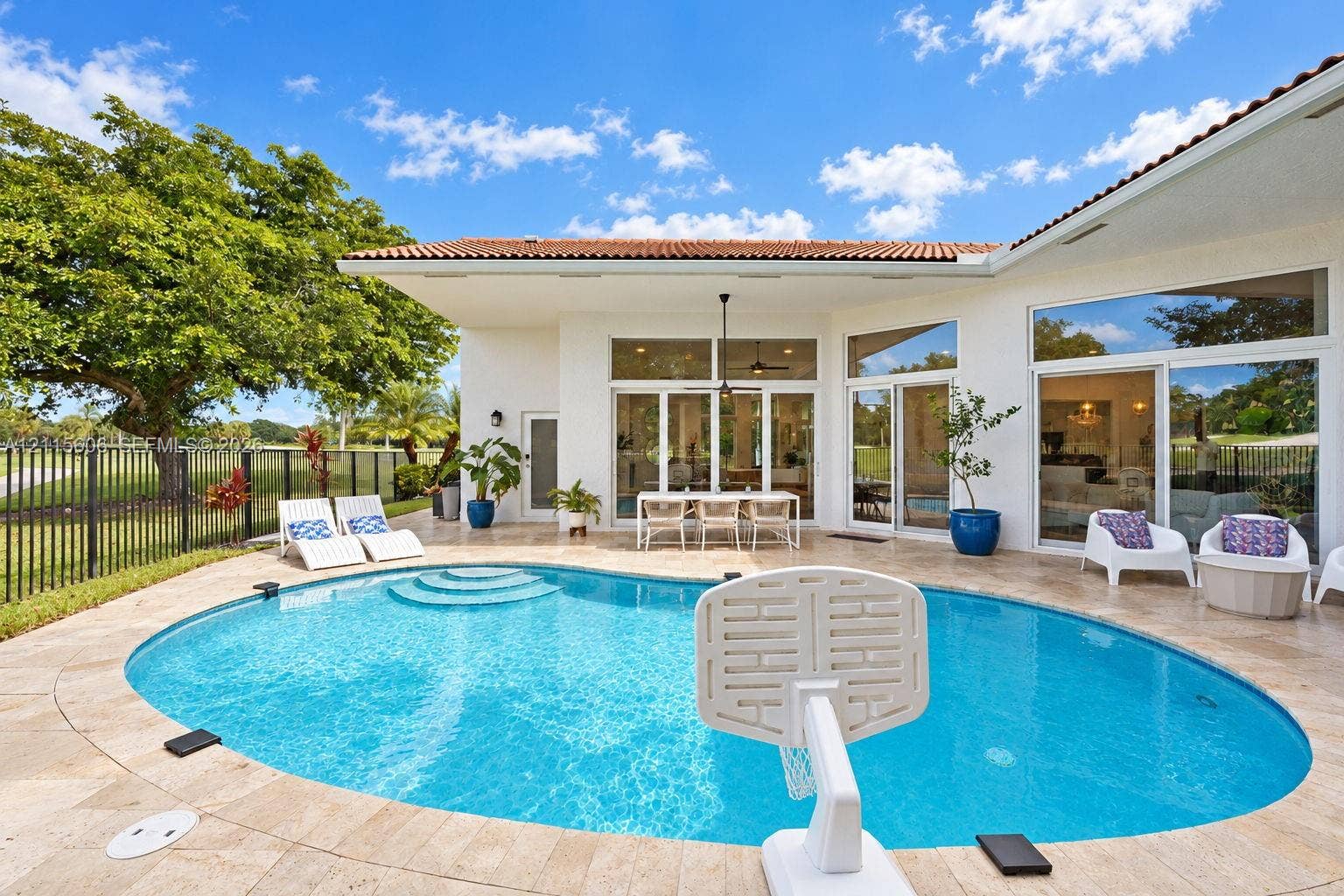 2652 Palmer Place, #2652, Weston, Weston, FL 33332 Outdoor patio featuring a travertine stone deck, a curved swimming pool with integrated steps, multiple floor-to-ceiling glass sliding doors, and a covered lanai