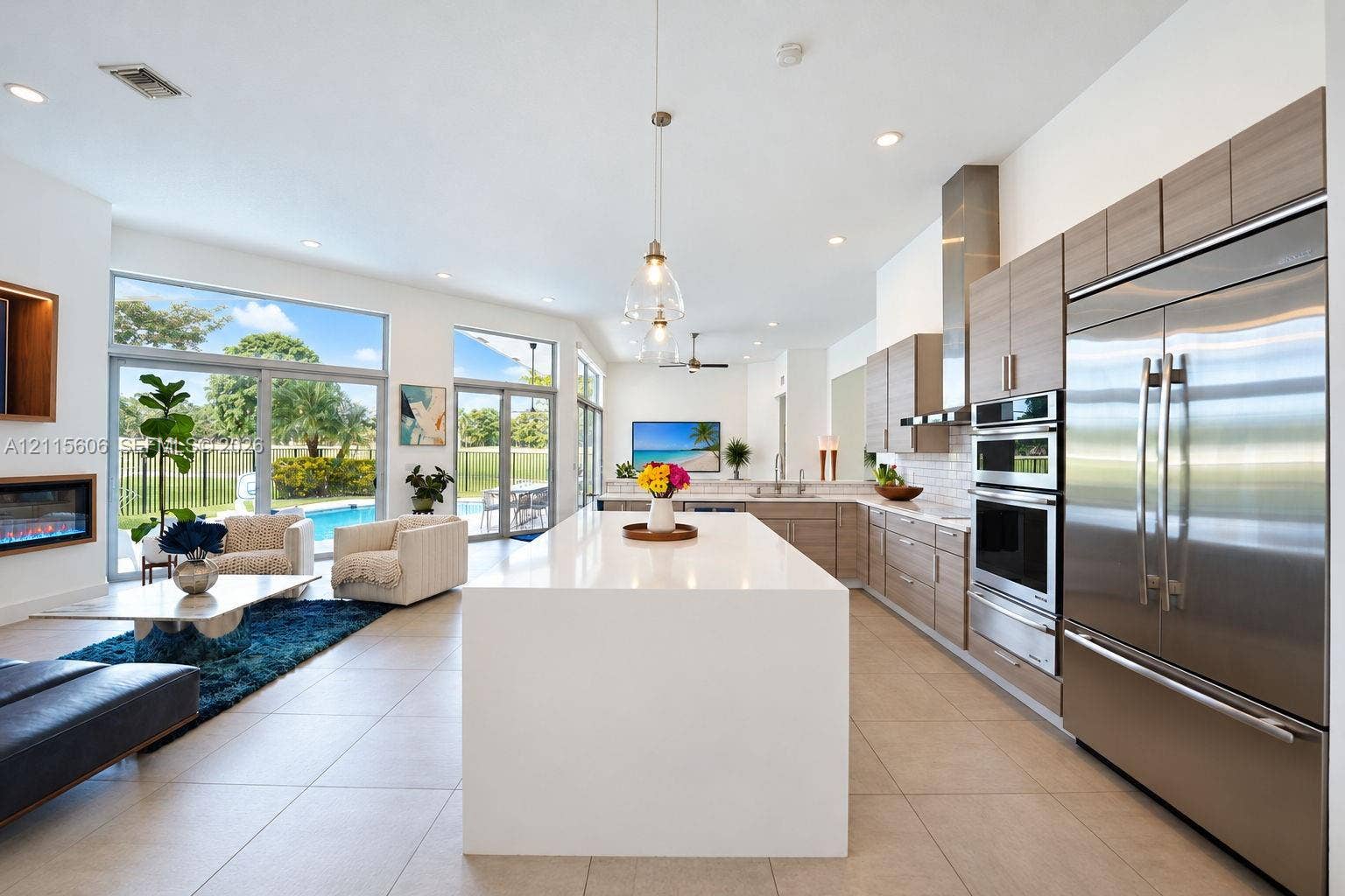 2652 Palmer Place, #2652, Weston, Weston, FL 33332 Open-concept interior featuring large center island with solid-surface countertop, linear wood-finish cabinetry, stainless steel built-in appliances, recessed lighting, and expansive sliding glass doors