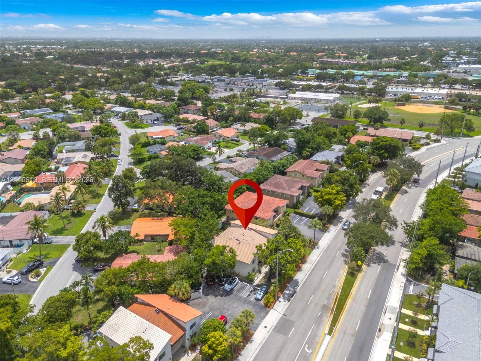 3711 Riverside Drive, Coral Springs, FL 33065 Aerial perspective featuring a tile-roofed structure with an integrated parking lot and mature tree canopy, situated within a suburban grid