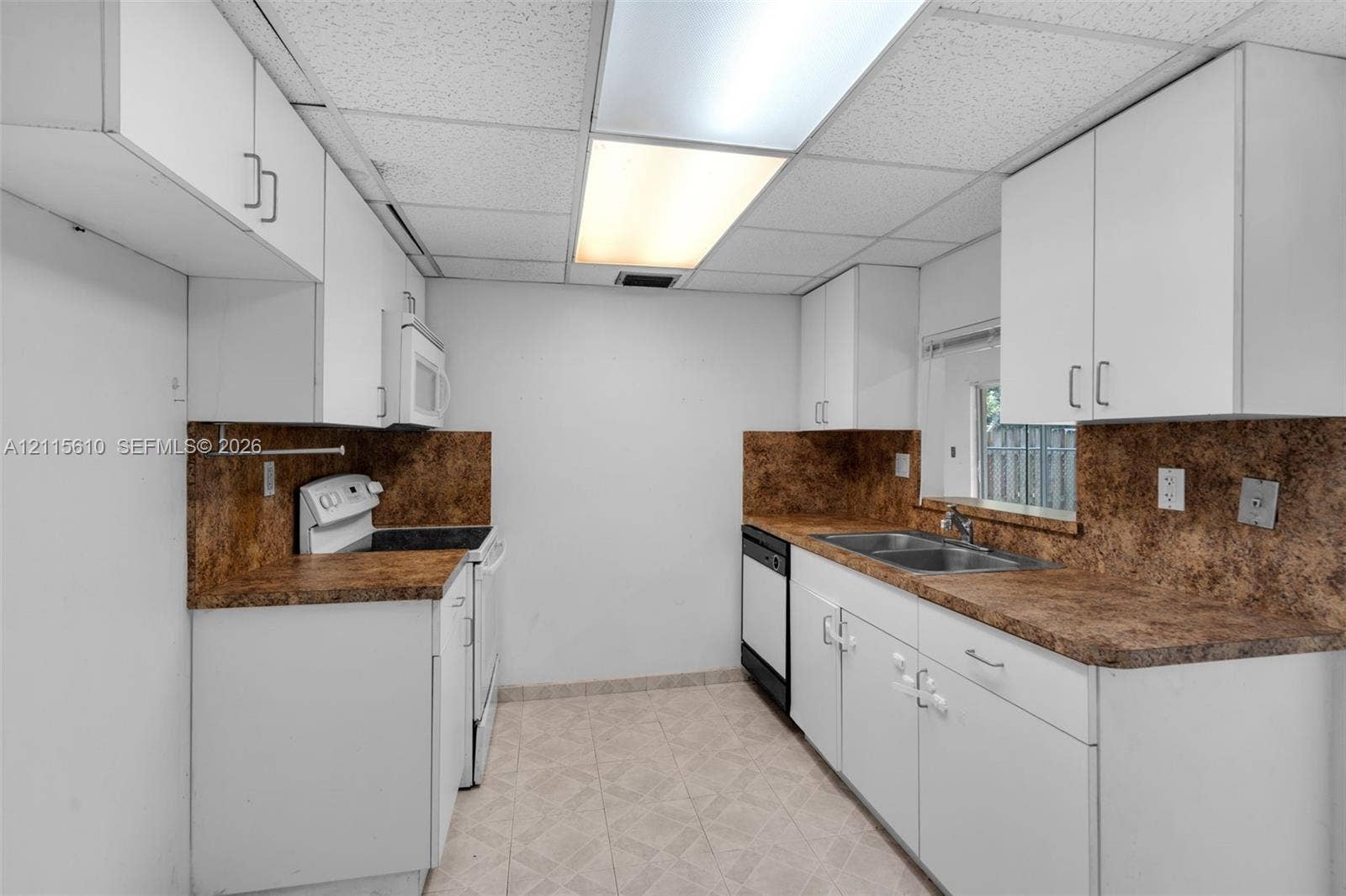 3711 Riverside Drive, Coral Springs, FL 33065 Kitchen featuring white cabinetry, patterned laminate countertops, dual-basin stainless steel sink, integrated dishwasher, and tiled flooring