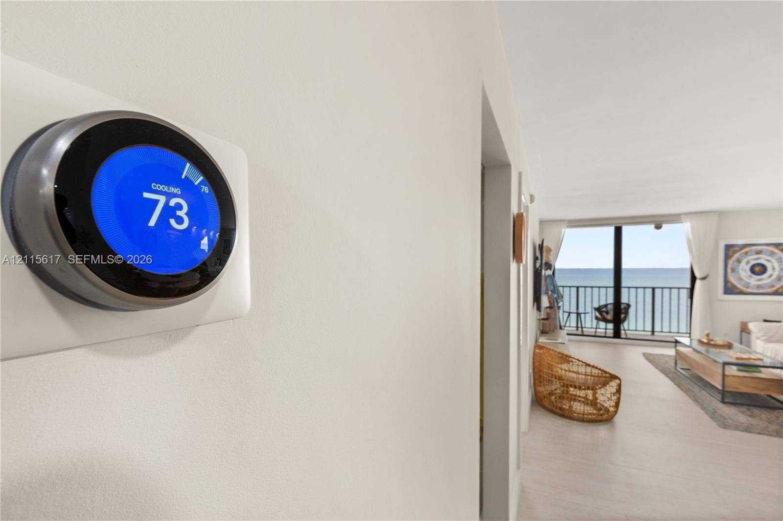 Smart thermostat with digital display, floor-to-ceiling windows, and private balcony with metal railing