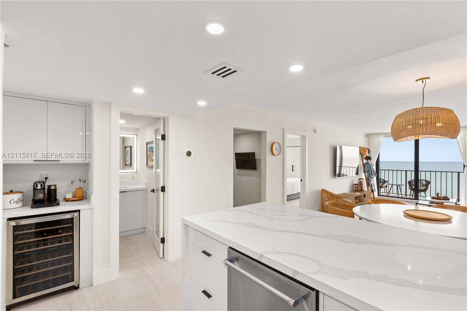 Kitchen featuring a large quartz-surface island, integrated wine refrigerator, recessed lighting, and balcony access with ocean water orientation