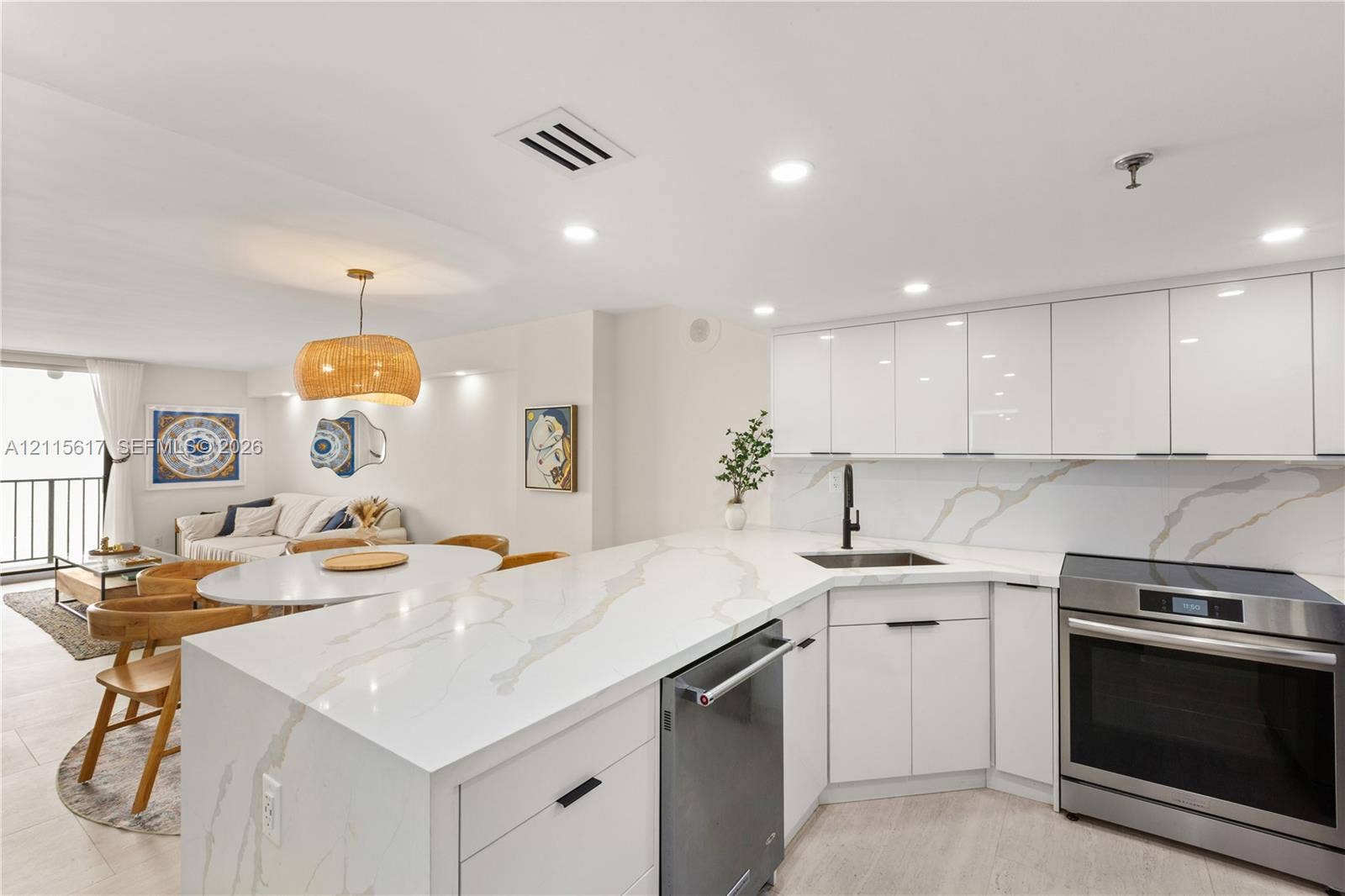 Kitchen featuring high-gloss white cabinetry, quartz countertops with integrated backsplash, stainless steel appliances, and a matte black faucet