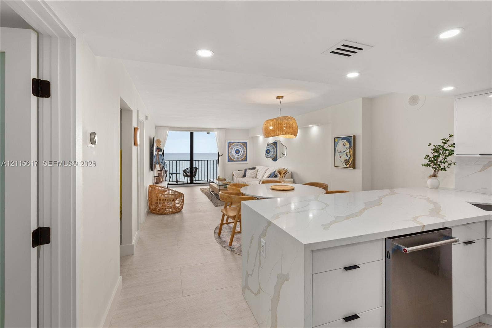 Kitchen featuring a stone-surface waterfall island, flat-panel cabinetry, stainless steel dishwasher, tile flooring, and recessed lighting