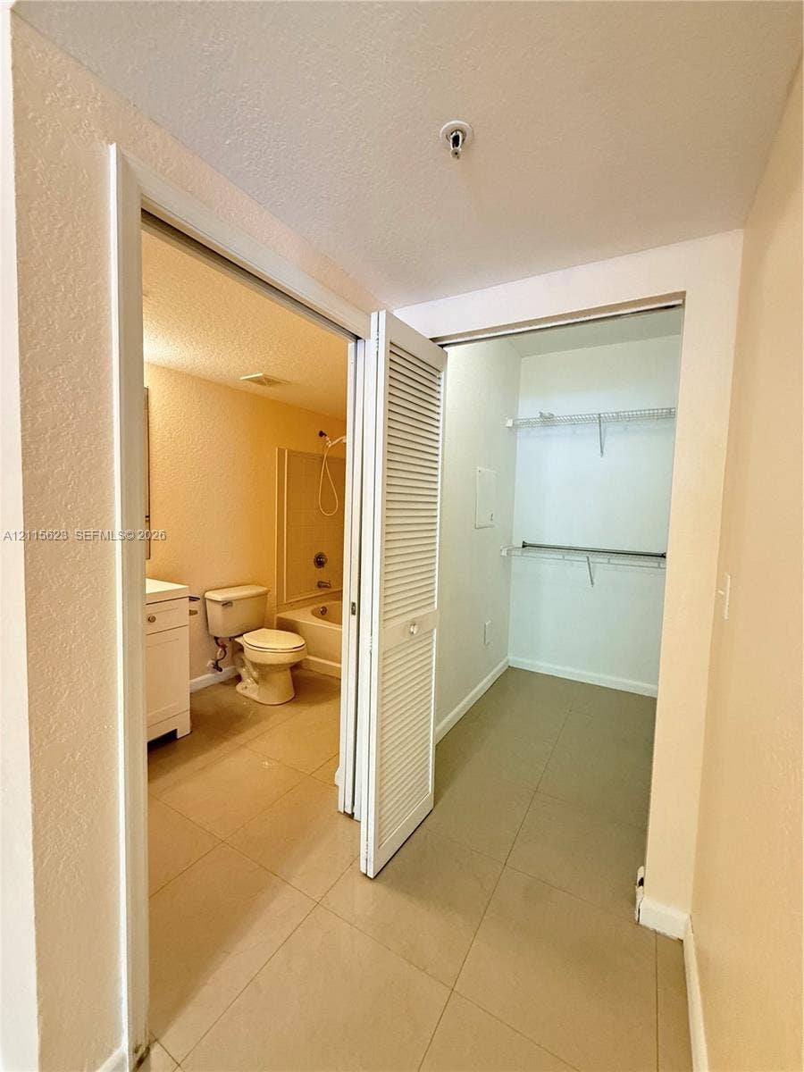 6796 W Sample Road, #6796, Coral Springs, Coral Springs, FL 33067 Bathroom featuring a white vanity cabinet, ceramic tile flooring, a tub-shower combination, and a walk-in closet with built-in metal shelving