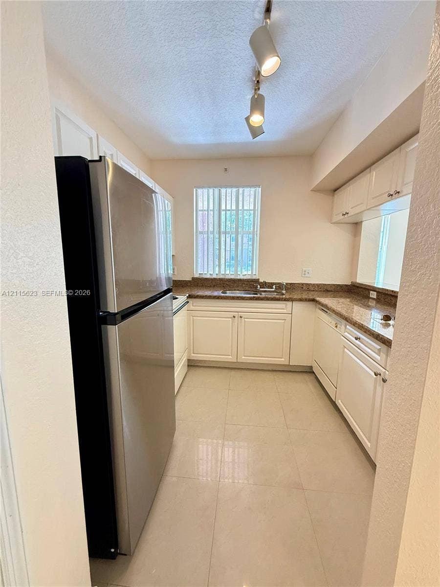6796 W Sample Road, #6796, Coral Springs, Coral Springs, FL 33067 Kitchen featuring white cabinetry, stone-finish countertops, tile flooring, stainless steel refrigerator, and dual-track ceiling lighting