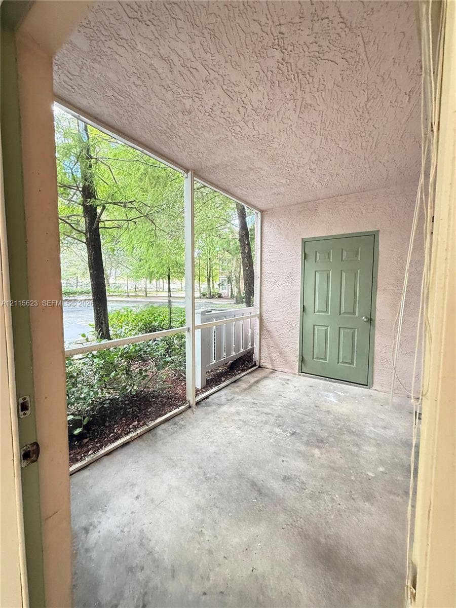 6796 W Sample Road, #6796, Coral Springs, Coral Springs, FL 33067 Screened patio featuring a concrete floor, textured ceiling, and a solid-panel door with metallic hardware
