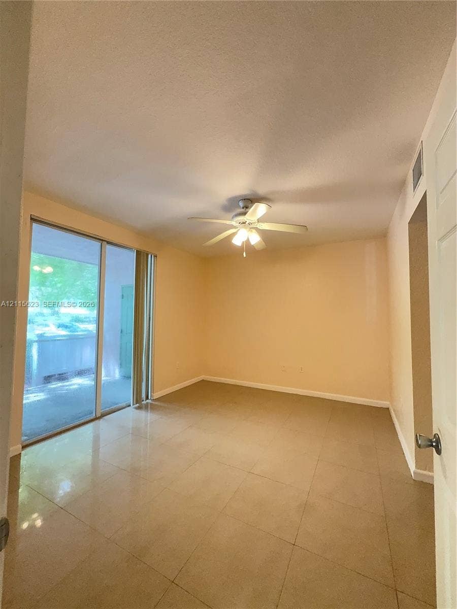 6796 W Sample Road, #6796, Coral Springs, Coral Springs, FL 33067 Large-format tile flooring, ceiling fan with integrated lighting, and sliding glass doors with direct access to an exterior patio