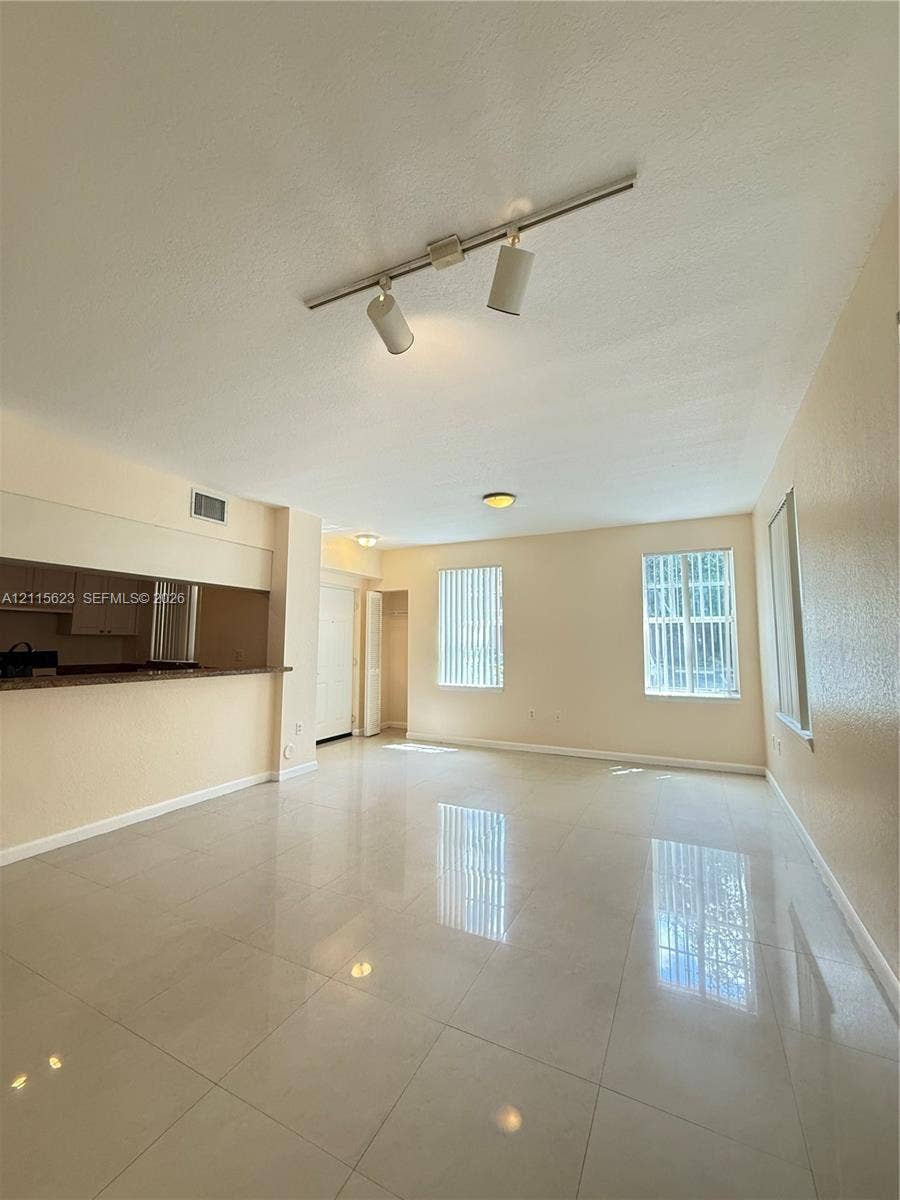 6796 W Sample Road, #6796, Coral Springs, Coral Springs, FL 33067 Open-concept living space featuring high-gloss tile flooring, adjustable track lighting, neutral wall finishes, and a pass-through service counter