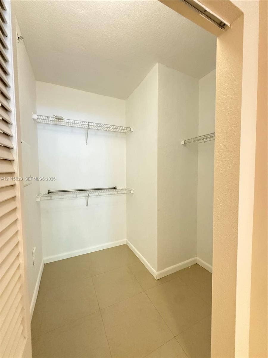 6796 W Sample Road, #6796, Coral Springs, Coral Springs, FL 33067 Storage space featuring white walls, large-format tile flooring, and tiered white wire shelving with integrated rods