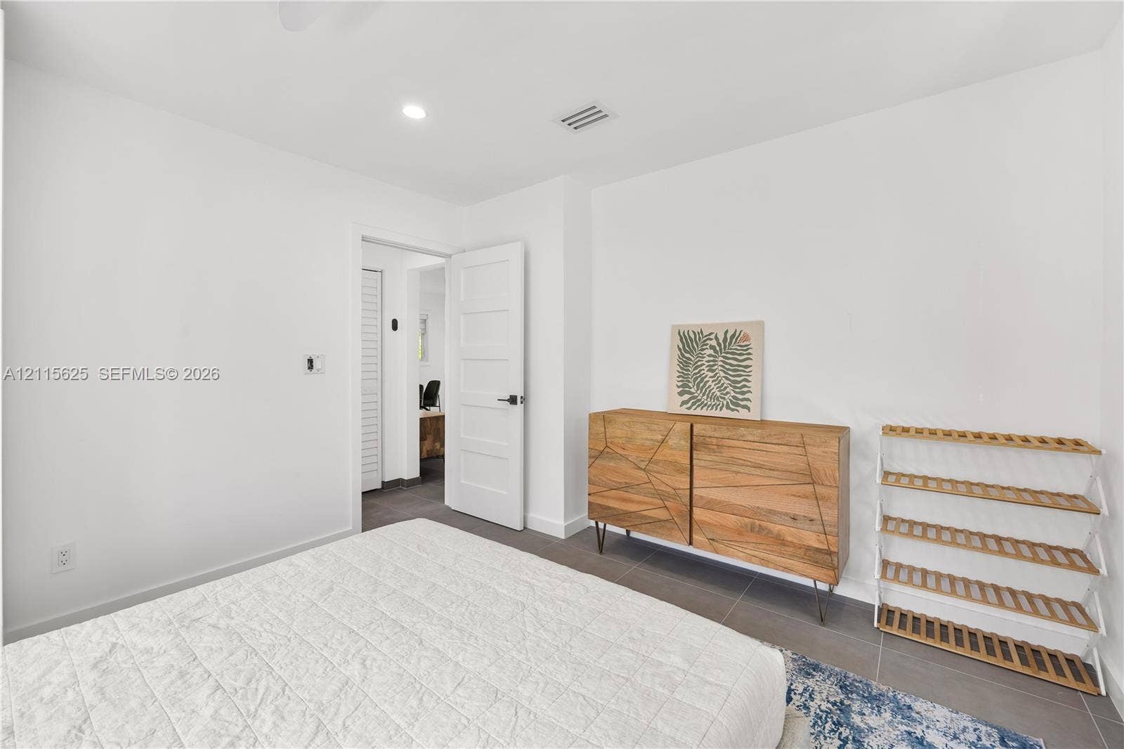 Interior room featuring neutral wall color, grey tile flooring, and a four-panel door with matte black hardware
