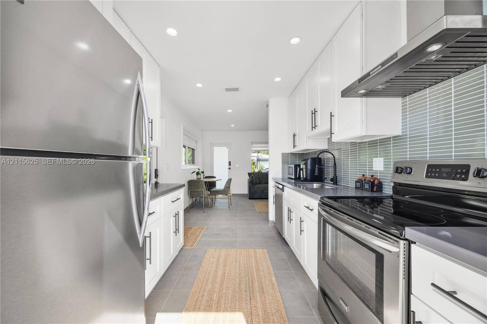 Kitchen featuring white cabinetry, gray countertops, stainless steel appliances, a glass-tiled backsplash, and recessed lighting