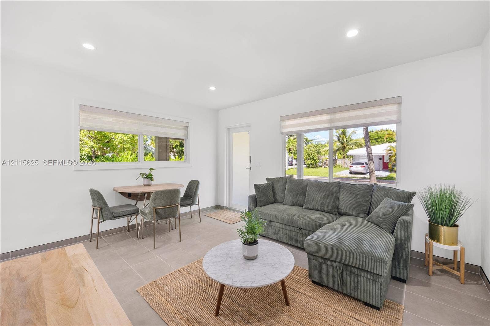 Bright interior featuring neutral wall tones, ceramic tile flooring, recessed ceiling lighting, and large windows with integrated roller shades