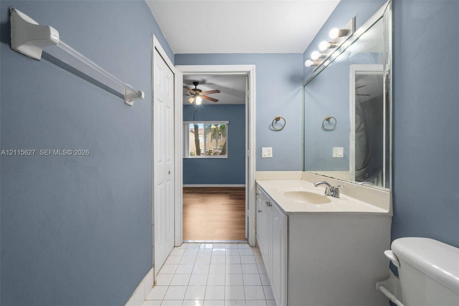 7085 Nova Drive, #218, Davie, FL 33317 Bathroom featuring a white vanity cabinet with an integrated sink, a full-width wall mirror, chrome fixtures, and white tile flooring