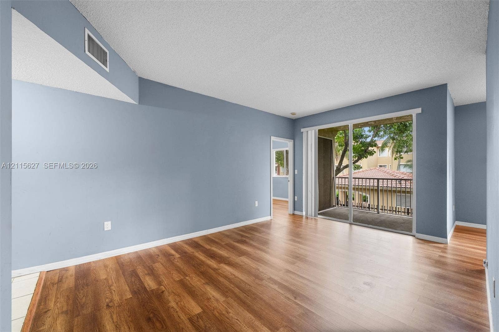 7085 Nova Drive, #218, Davie, FL 33317 Living area featuring wood-finish flooring, vaulted ceiling, and sliding glass doors leading to a private balcony