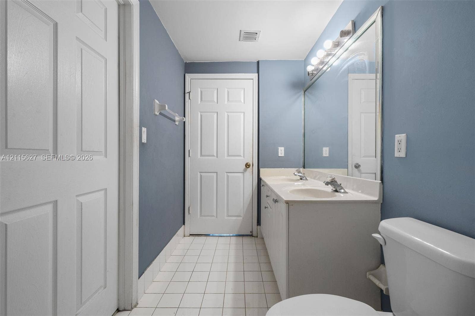 7085 Nova Drive, #218, Davie, FL 33317 Dual-sink vanity with a solid-surface countertop, full-width vanity mirror, polished chrome fixtures, and tiled flooring