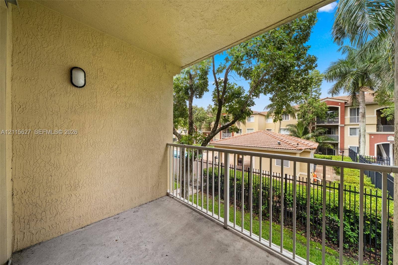 7085 Nova Drive, #218, Davie, FL 33317 Private balcony featuring a concrete floor, textured stucco walls, an attached wall-mounted light fixture, and a metal railing