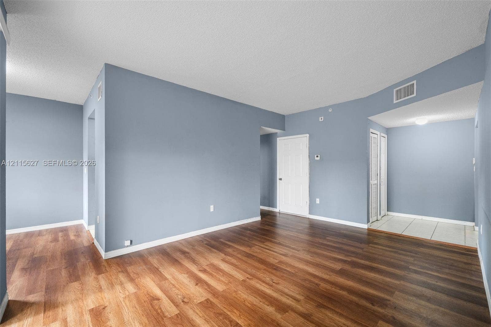 7085 Nova Drive, #218, Davie, FL 33317 Open-concept interior featuring wood-finish flooring, textured ceiling, six-panel interior doors, and neutral wall tones