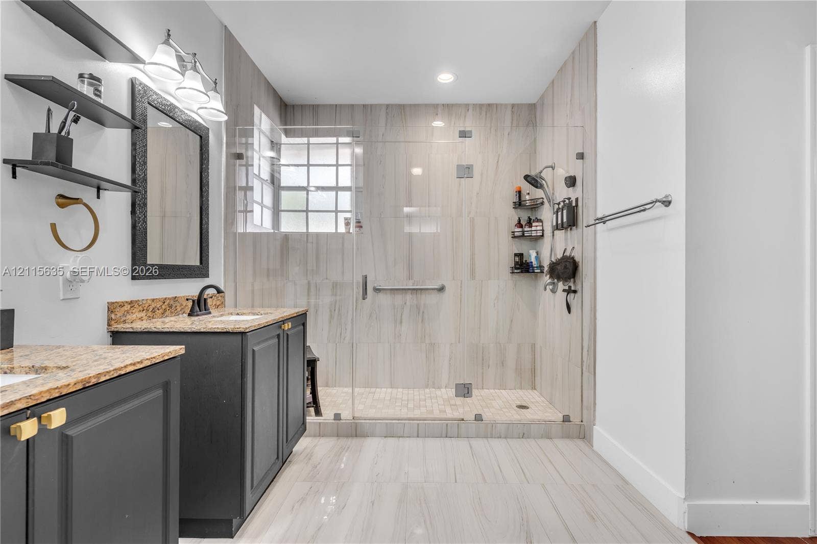 15374 SW 113th Terrace, Miami, FL 33196 Bathroom featuring a dark wood-finish vanity with stone-surfaced countertop, walk-in shower with floor-to-ceiling tile, glass enclosure, and glass block window