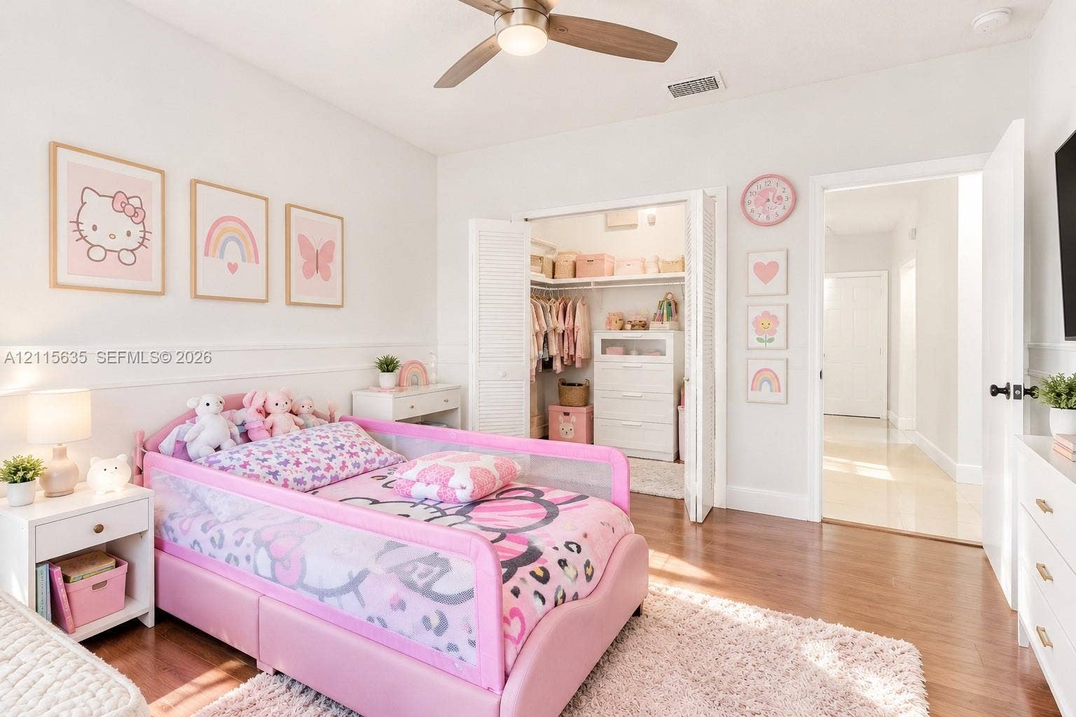 15374 SW 113th Terrace, Miami, FL 33196 Bedroom featuring wood-finish flooring, a ceiling fan with integrated lighting, white wainscoting, and a walk-in closet with louvered double doors