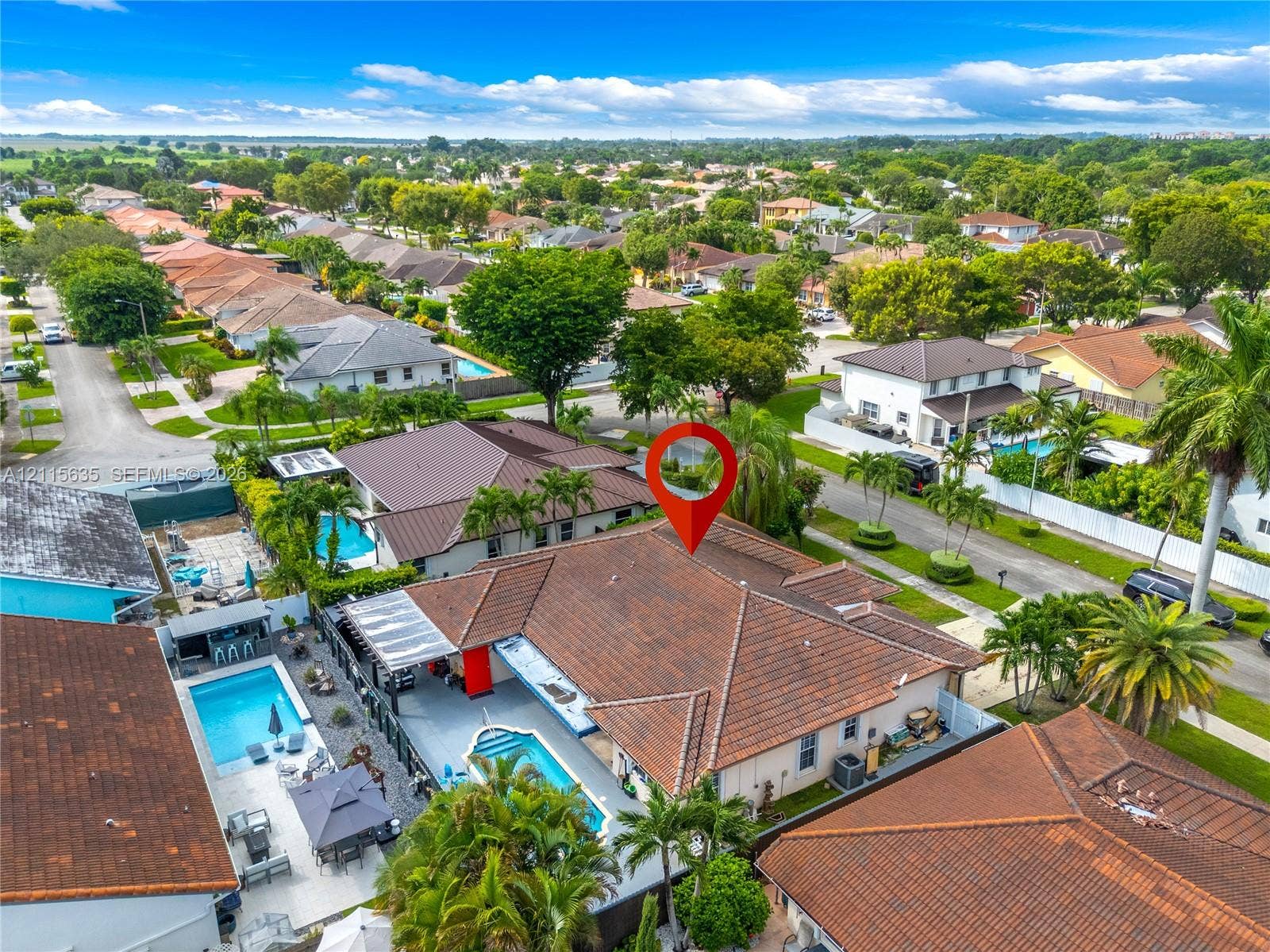 15374 SW 113th Terrace, Miami, FL 33196 Aerial perspective of a property featuring a tile roof, an in-ground swimming pool, a concrete patio area, and mature landscaping