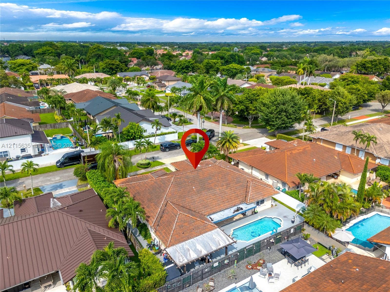 15374 SW 113th Terrace, Miami, FL 33196 Aerial perspective of a property featuring a tile roof, an in-ground swimming pool, a paved patio area, and mature palm trees