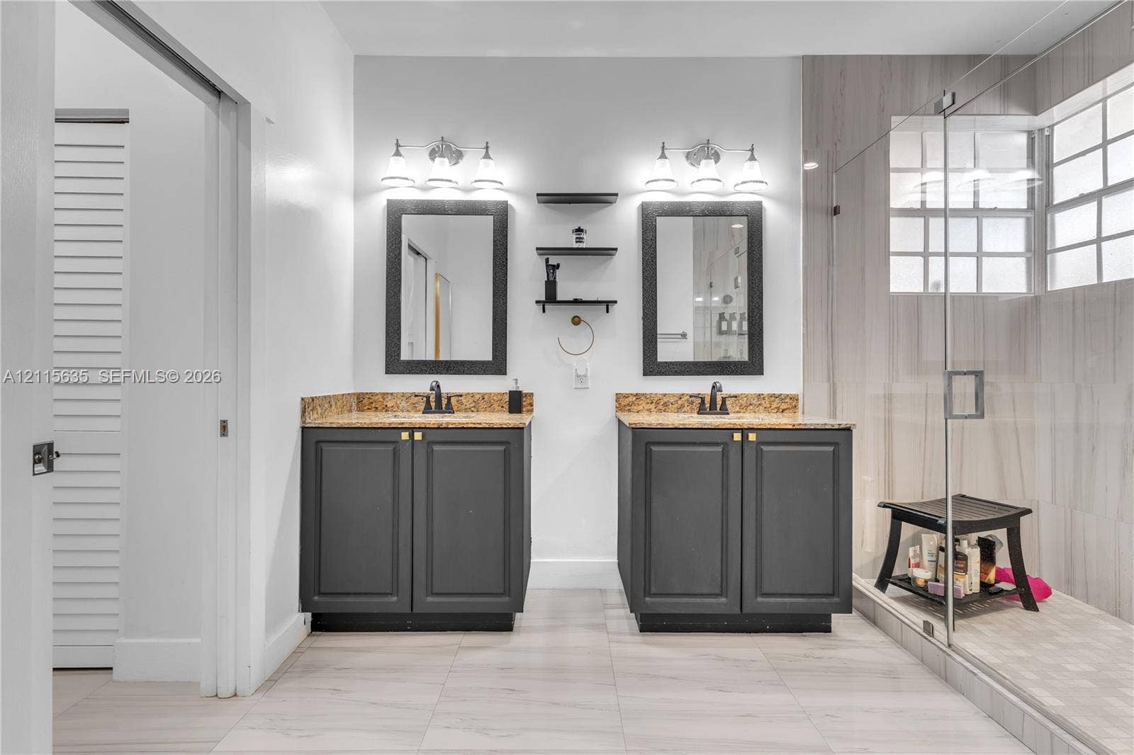 15374 SW 113th Terrace, Miami, FL 33196 Dual-vanity bathroom featuring stone-surfaced countertops, charcoal-finish cabinetry, framed mirrors, and a glass-enclosed shower with tiled wall surrounds