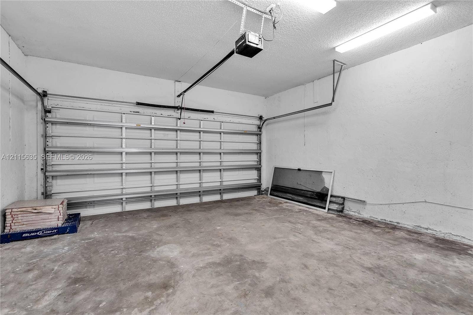 15374 SW 113th Terrace, Miami, FL 33196 Attached garage featuring concrete flooring, an automated overhead door system, and ceiling-mounted fluorescent lighting