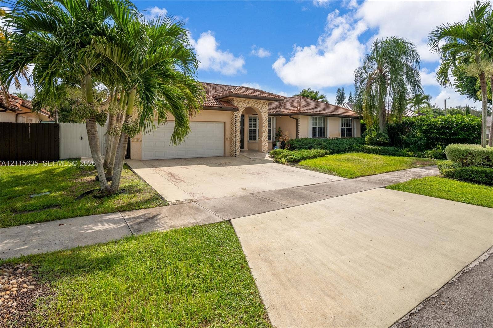 15374 SW 113th Terrace, Miami, FL 33196 Single-story residence featuring a tile roof, masonry exterior, arched entryway, concrete driveway, and mature palm landscaping