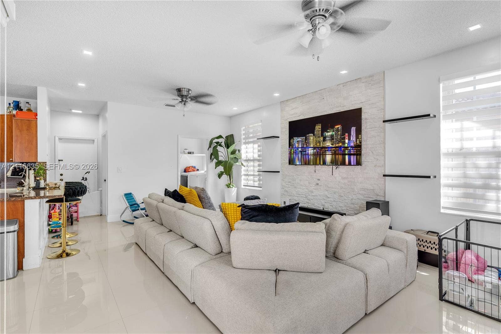 15374 SW 113th Terrace, Miami, FL 33196 Living area featuring a floor-to-ceiling natural stone veneer accent wall, recessed lighting, ceiling fans, large-format tile flooring, and integrated wall-mounted shelving