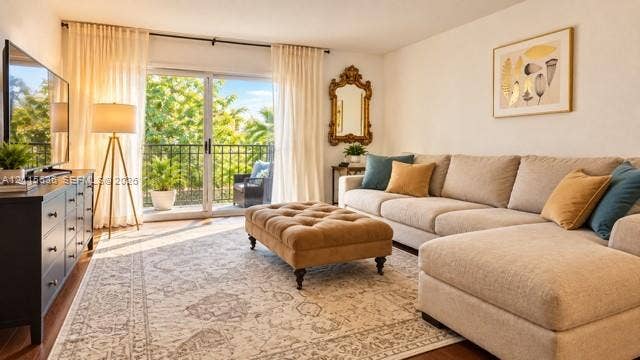 3860 NE 170th Street, #310, North Miami Beach, FL 33160 Living area featuring sliding glass doors, a wrought-iron balcony railing, and wood-finish flooring