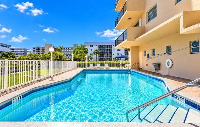 3860 NE 170th Street, #310, North Miami Beach, FL 33160 Swimming pool with integrated steps, tile border, surrounding perimeter fencing, and concrete decking