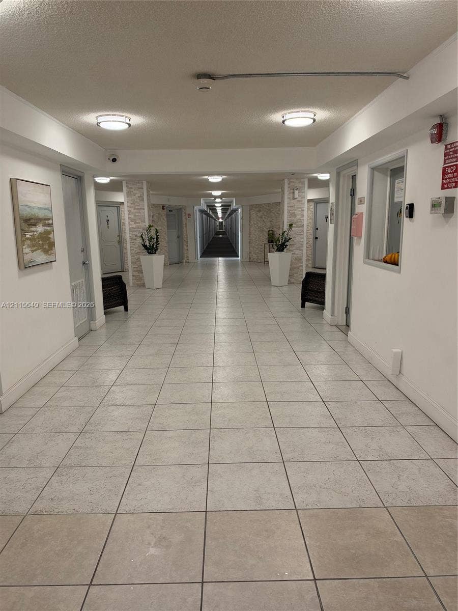 1913 S Ocean Drive, #426, Hallandale Beach, Hallandale Beach, FL 33009 Interior corridor featuring neutral tile flooring, stone-accented structural columns, and recessed lighting