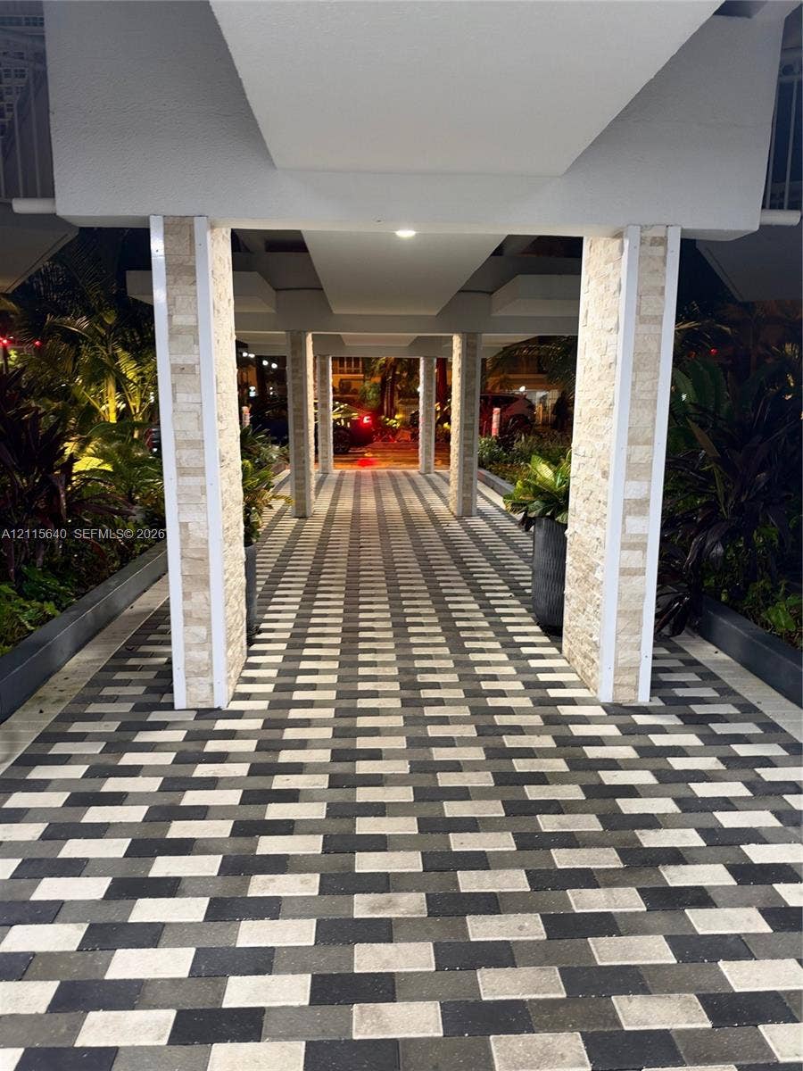 1913 S Ocean Drive, #426, Hallandale Beach, Hallandale Beach, FL 33009 Covered walkway featuring a geometric paver path, tiered stone-cladding columns, and integrated recessed ceiling lighting
