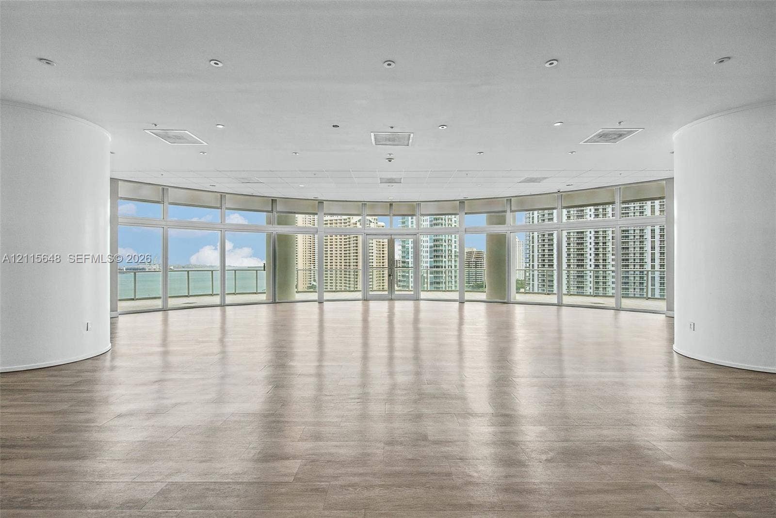 300 S Biscayne Boulevard, #T-3604, Miami, FL 33131 Curved interior wall architecture featuring floor-to-ceiling windows, wood-finish flooring, recessed lighting, and a wrap-around balcony