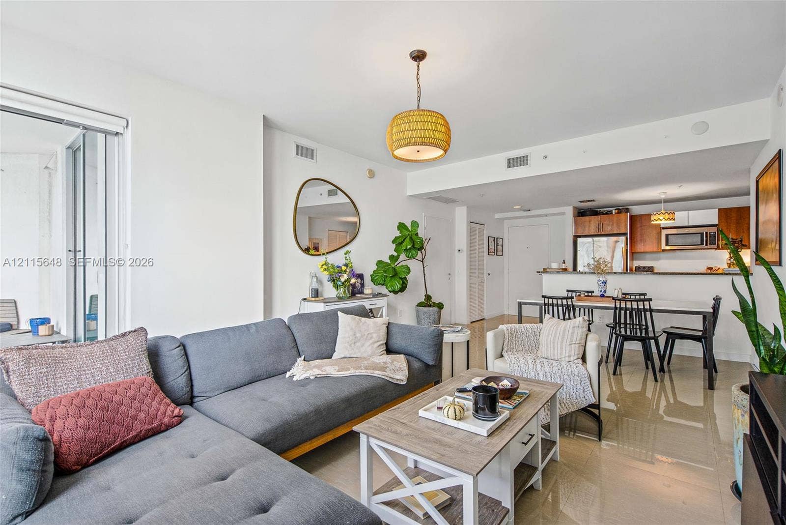 300 S Biscayne Boulevard, #T-3604, Miami, FL 33131 Open-concept interior featuring large-format tile flooring, a kitchen with wood-finish cabinetry, a breakfast bar, and a woven pendant light fixture