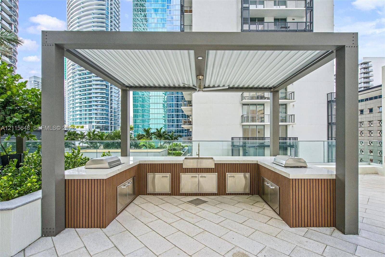 300 S Biscayne Boulevard, #T-3604, Miami, FL 33131 Outdoor kitchen featuring a structural metal pergola, stone-paver flooring, built-in stainless steel cabinetry, integrated cooktops, and a central basin