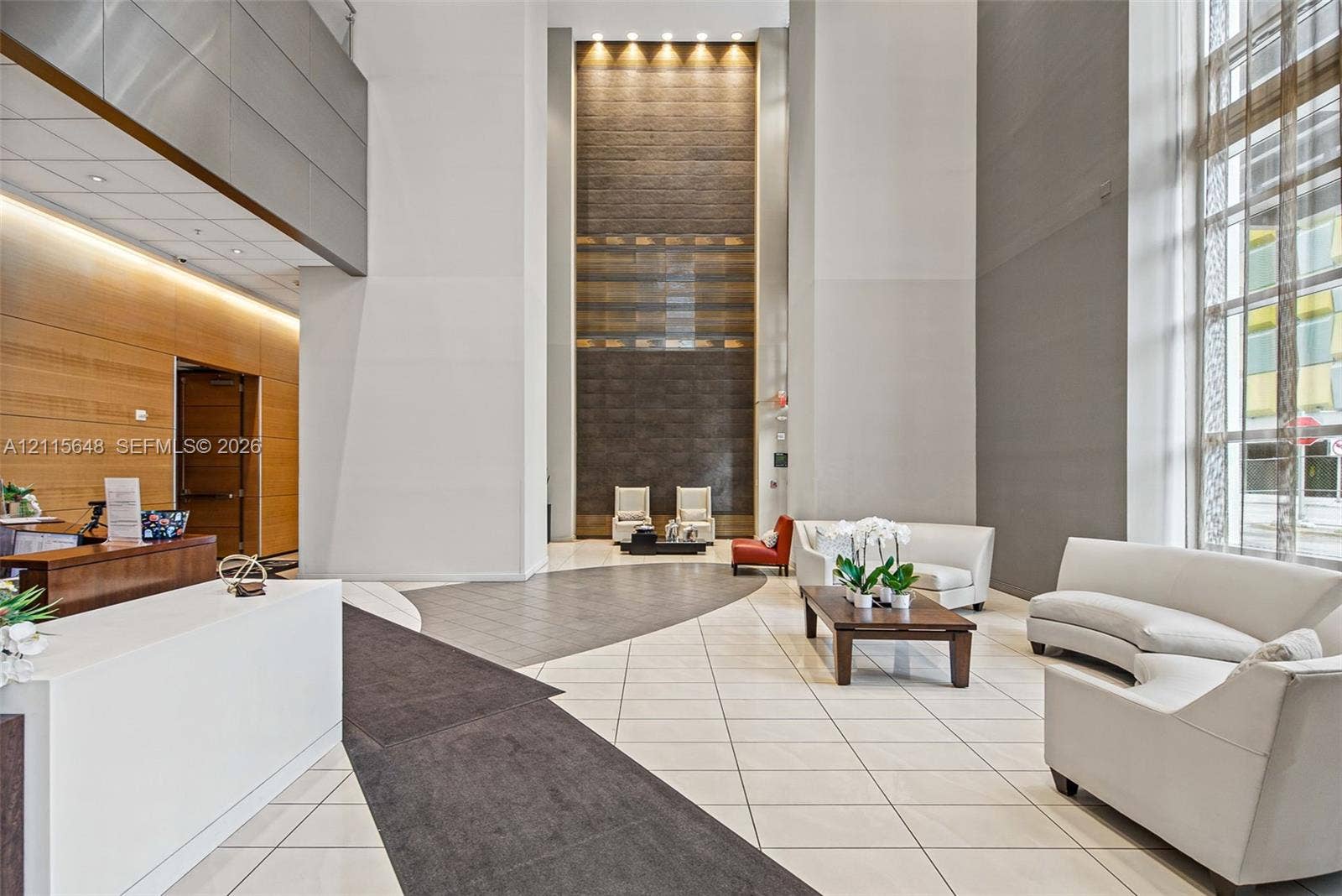 300 S Biscayne Boulevard, #T-3604, Miami, FL 33131 Grand lobby featuring double-height ceilings, a floor-to-ceiling textured accent wall, polished stone flooring, recessed architectural lighting, and floor-to-ceiling windows