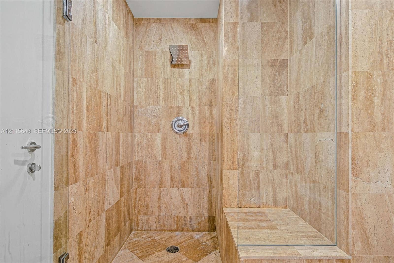 300 S Biscayne Boulevard, #T-3604, Miami, FL 33131 Walk-in shower featuring floor-to-ceiling stone tile, a built-in tiled bench, a glass enclosure, and a circular wall-mounted shower fixture