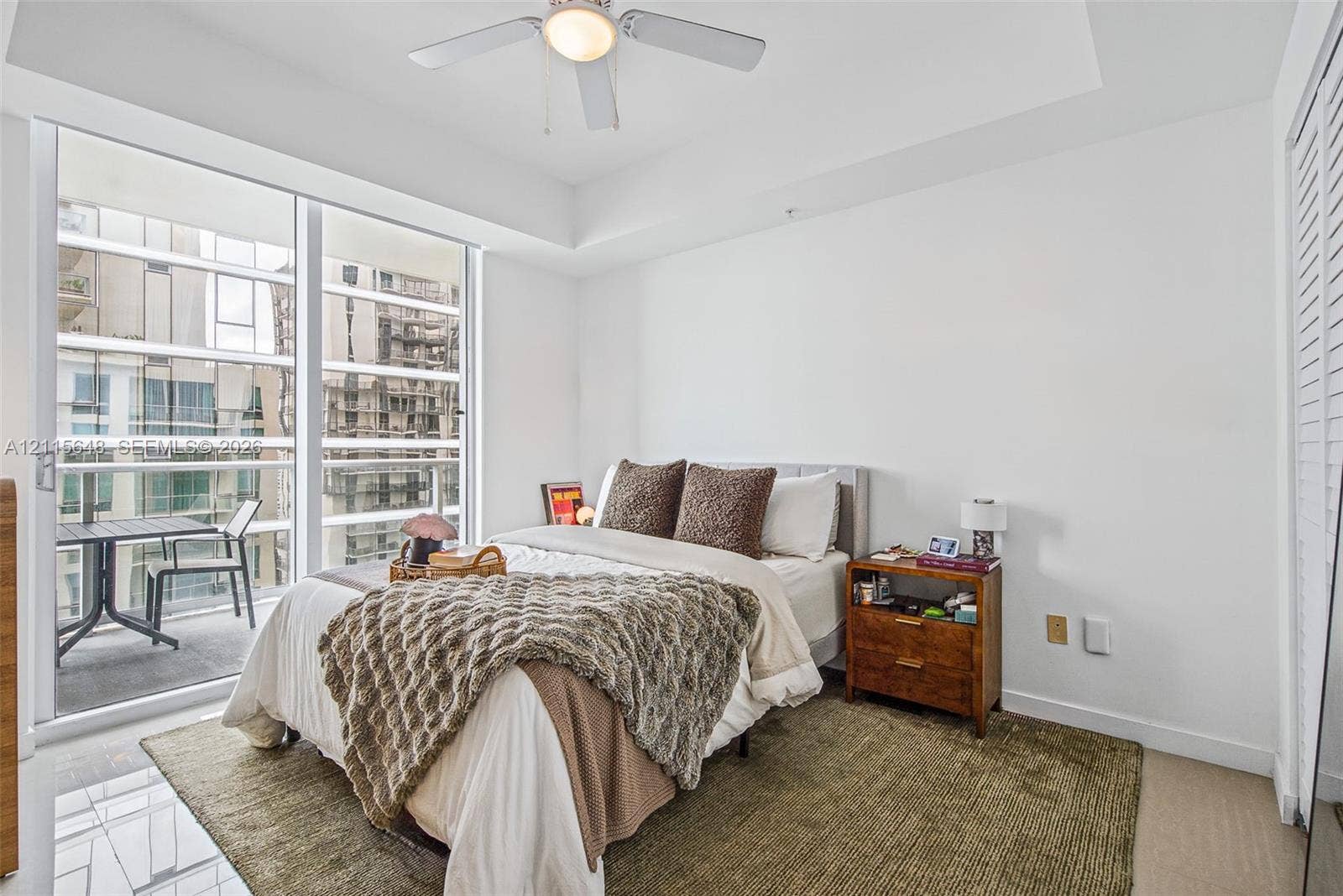 300 S Biscayne Boulevard, #T-3604, Miami, FL 33131 Floor-to-ceiling glass sliding doors, tray ceiling, ceiling fan with integrated light, and louvered closet doors