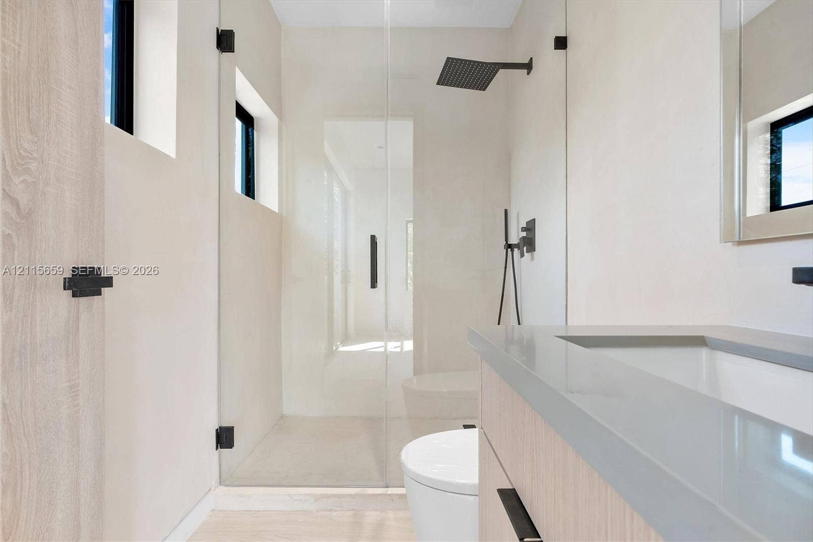 4719 N Miami Avenue, Miami, FL 33127 Bathroom featuring a wood-finish vanity with a stone countertop, a glass-enclosed walk-in shower with matte black rainfall showerhead, and high-contrast matte black hardware
