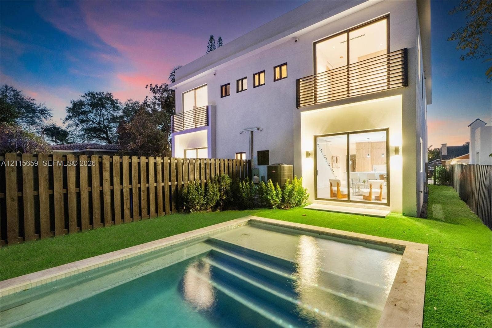4719 N Miami Avenue, Miami, FL 33127 Two-story exterior with stucco finish, in-ground swimming pool, horizontal slat balcony railings, sliding glass doors, and privacy fencing