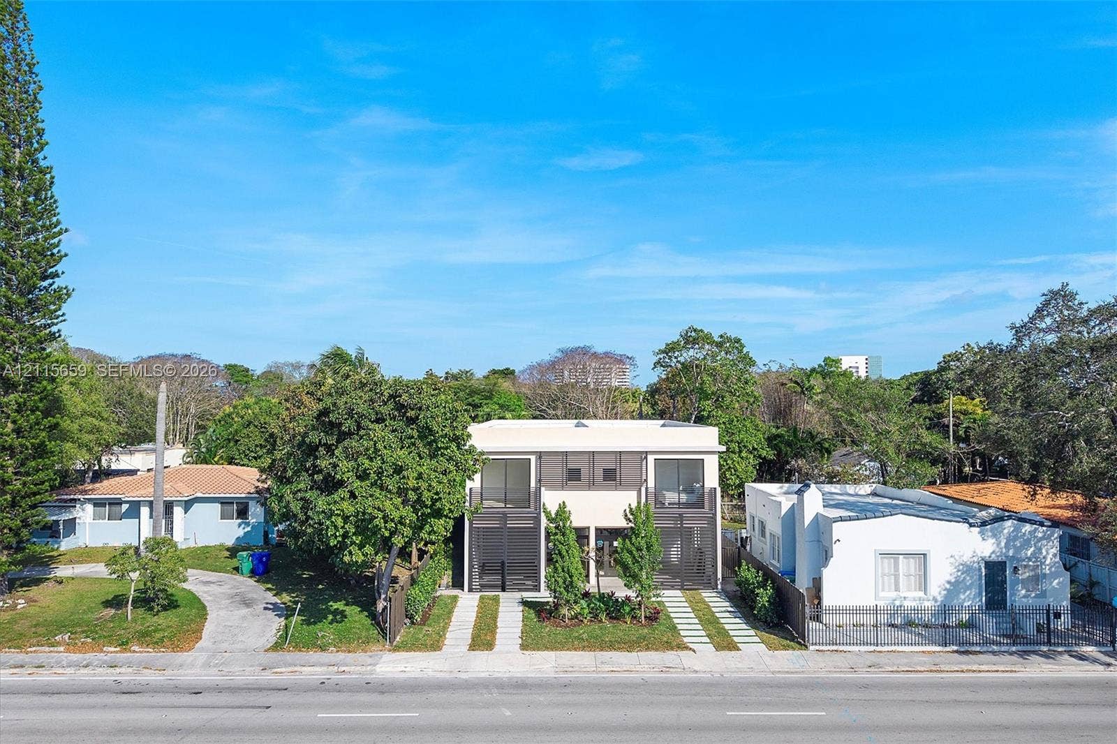 4719 N Miami Avenue, Miami, FL 33127 Modern two-story structure featuring a stucco exterior, integrated balconies, large-format glass doors, and a paved dual-track driveway