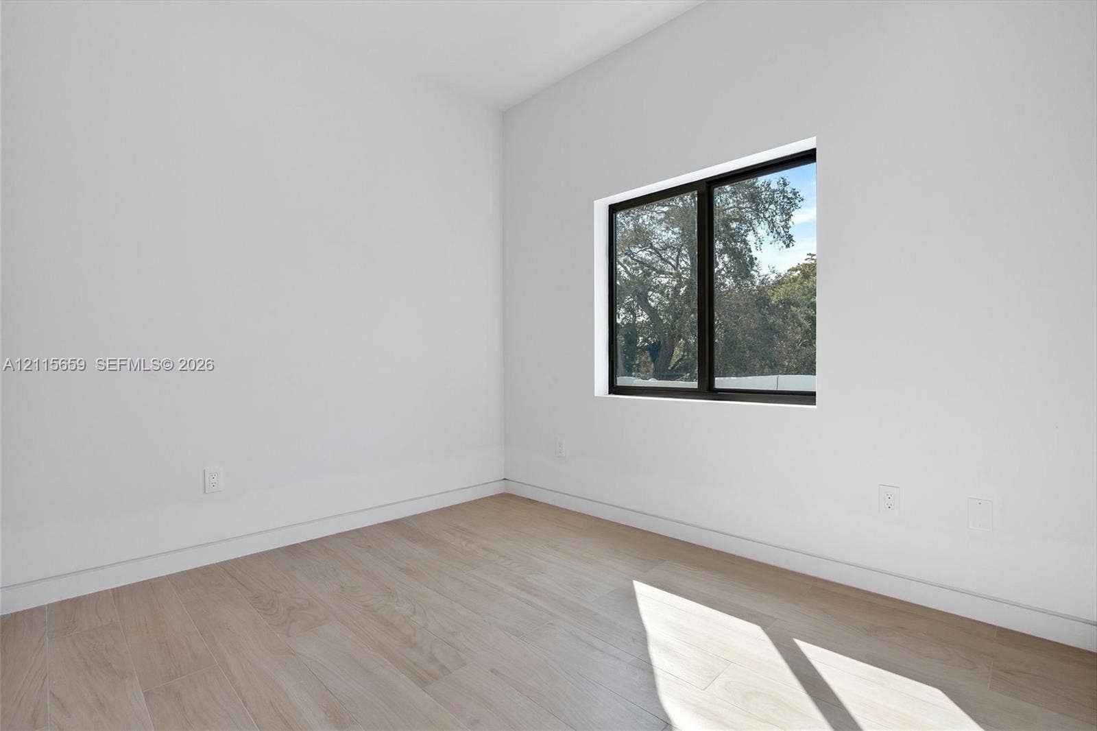 4719 N Miami Avenue, Miami, FL 33127 Interior space featuring neutral wall tones, wood-finish flooring, and a black-framed window
