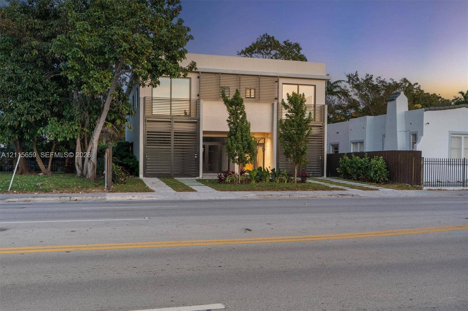 4719 N Miami Avenue, Miami, FL 33127 Contemporary two-story exterior featuring a smooth stucco facade, floor-to-ceiling glass doors, decorative metal screening, and upper-level balconies