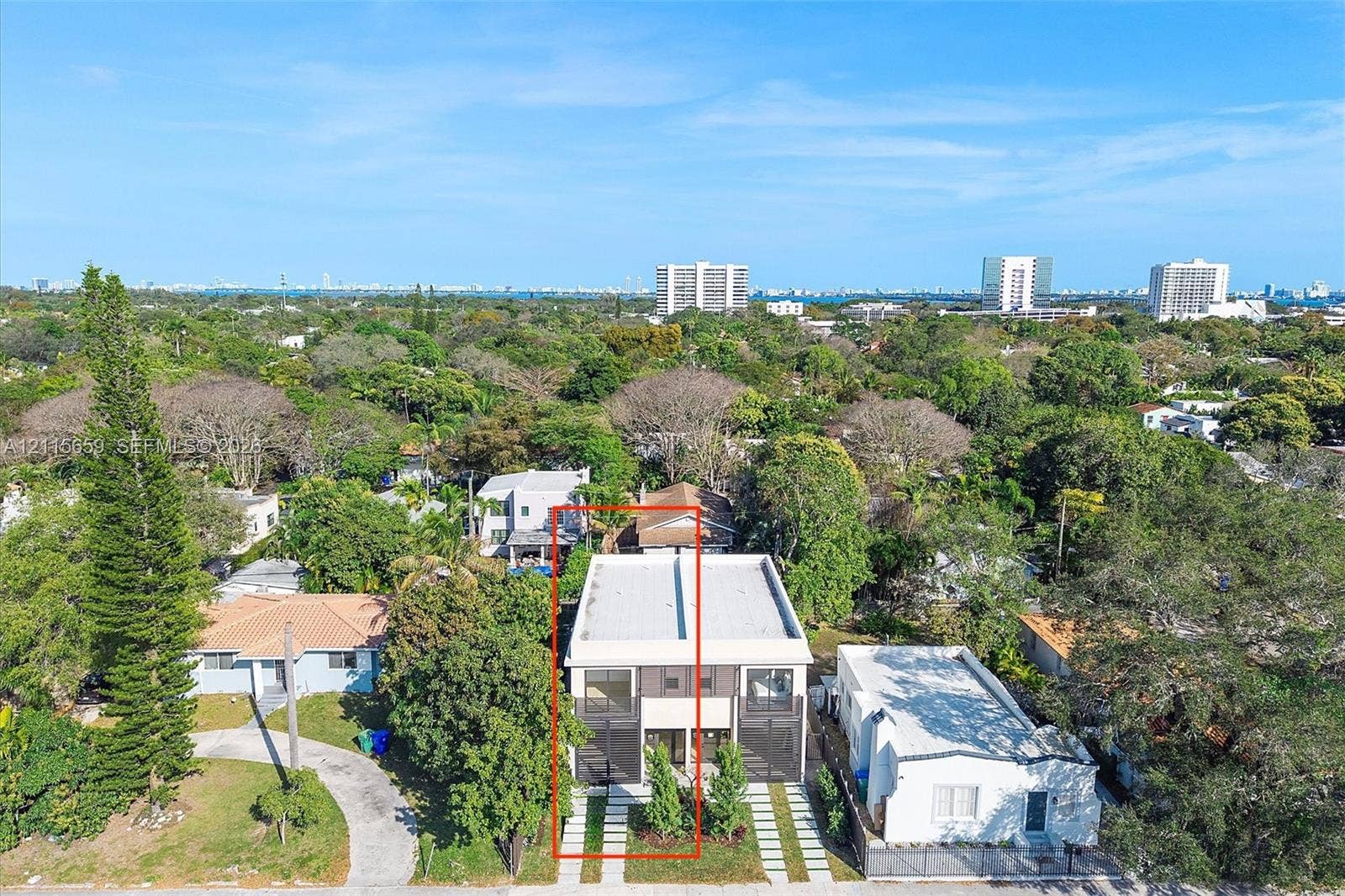4719 N Miami Avenue, Miami, FL 33127 Two-story residence featuring a flat roofline, multi-level balconies, large glass sliding doors, and a paver-style driveway