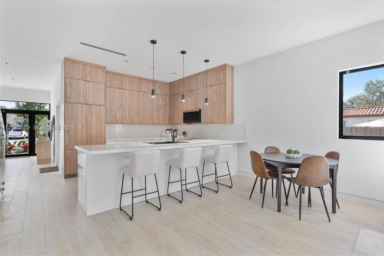 4719 N Miami Avenue, Miami, FL 33127 Modern kitchen featuring wood-finish cabinetry, a white countertop island, integrated lighting pendants, and light-toned tile flooring