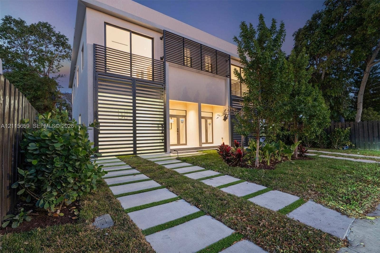 4719 N Miami Avenue, Miami, FL 33127 Contemporary two-story exterior featuring a smooth stucco finish, horizontal metal louvered privacy screening, glass sliding doors, and a linear paver driveway